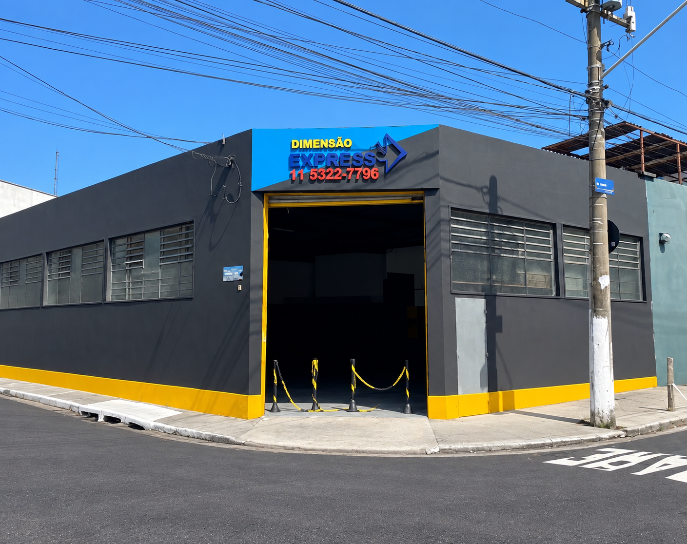 Fachada da sede da Dimensão Express em São Paulo, com o logo da empresa e portão de expedição aberto
